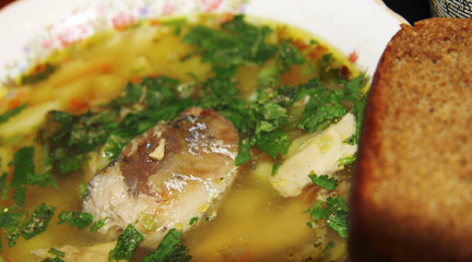 Fish soup in the white bowl with herbs and spoon