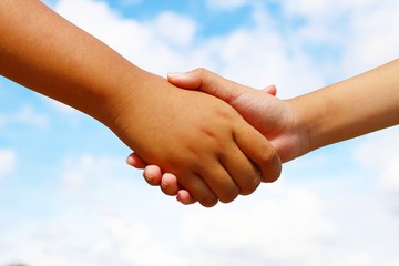 Kids holding hands or shaking hands with blue sky background