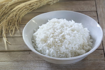 Jasmine rice in  bowl and paddy rice on a brown wooden background beautiful Thai food