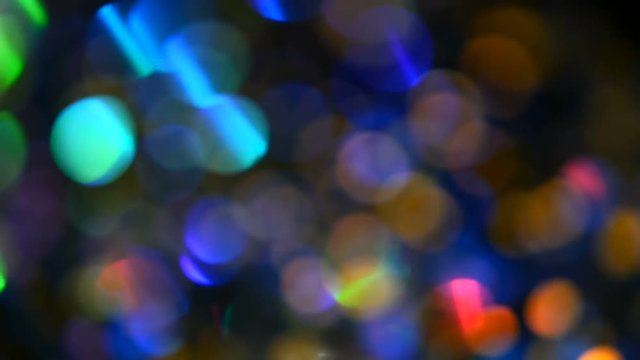 Defocused shimmering multicolored glitter confetti, black background. Party, magic, imagination. Rainbow colors, sparkle circles. Holiday abstract festive texture of shiny blurred bokeh light spots.