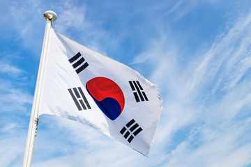 Korean flag with wind on blue sky with light white clouds