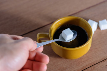 The hand is filling the sugar into the coffee..