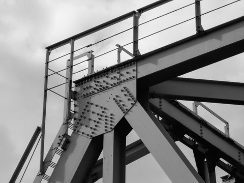 Fototapeta Fragment of metal train track bridge in the industrial area. Bottom view. Urban grunge. Black and white photo