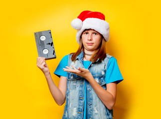 portrait of young teenage girl in Christmas hat with VHS on yellow background