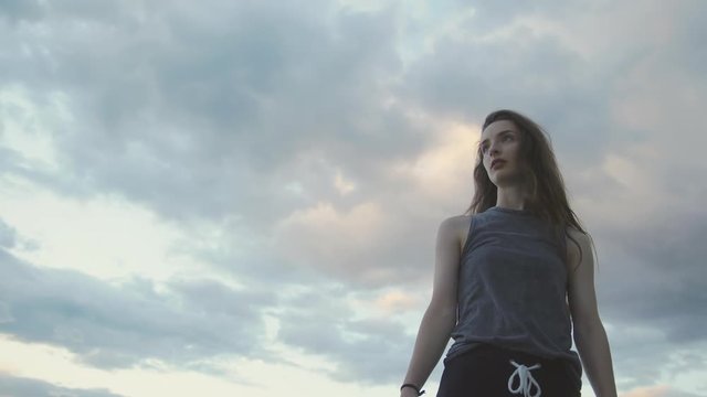 Teenager dances slow, camera moving towards sunset sky