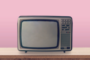 Vintage TV box on wooden table and pink pastel color background.