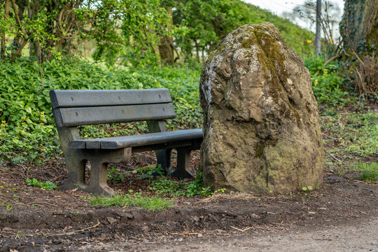 A bench with a large stone in front of it, seen between Church Stretton and Hope Bowdler, Shropshire, England, UK