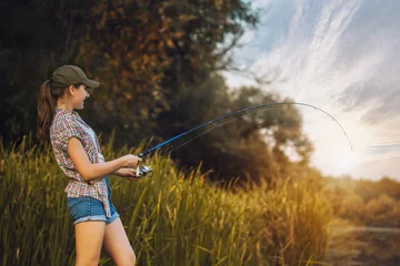 Fotobehang Cute woman is fishing with rod on lake © Dmytro Titov