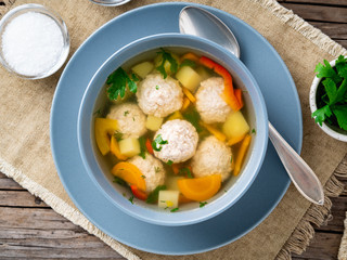 soup with meatballs in blue plate on old wooden rustic grey table, top view, close up