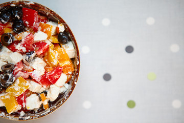 delicious salad with olives, feta pepper, tomato, cucumber and olive oil in an ethnic plate on a polka-dot stand