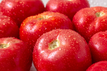 Washed for dinner, red tomatoes. Splashes and drops of water on vegetables and in the background