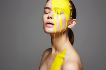 Young woman in Yellow paint. liquid paint flowing