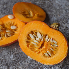 Fresh organic pumpkin in slices on dark stone table. Autumn harvest, healthy lifestyle, raw vegetables, selective focus. Halloween background