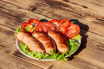 Grilled sausages with fresh vegetables on wooden table