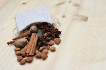 Fototapeta na wymiar Concept with ingredients for chocolate, cocoa beans, cinnamon, anise, apricot beans coming out of a little bag on natural wood background, side view, selective focus, copy space
