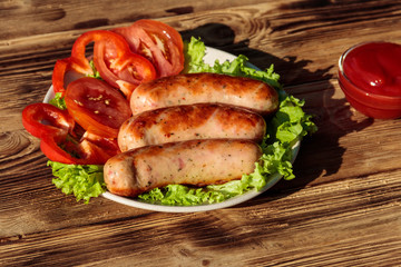 Grilled sausages with fresh vegetables and tomato sauce on wooden table