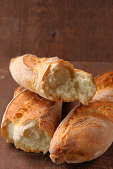 Fresh baguette broken half on a wooden table