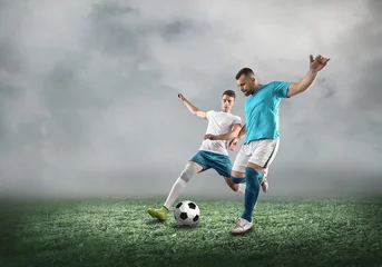 Foto op Plexiglas Soccer player on a football field in dynamic action at summer day © Andrii IURLOV
