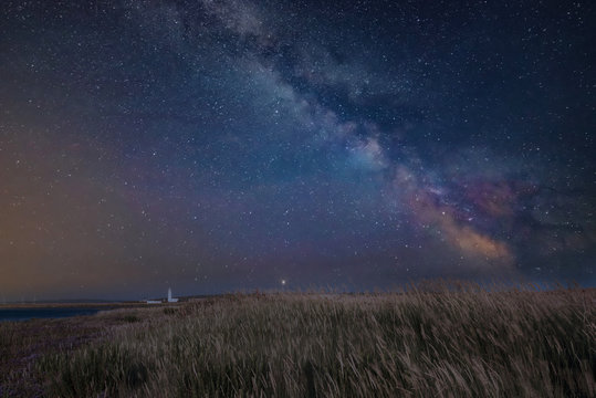 Vibrant Milky Way composite image over landscape of Lighthouse