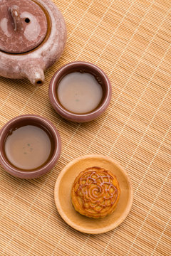 top view studio shoot of traditional Chinese mooncake with tea and teapot on bamboo mat vertical composition