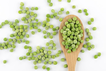 Guisantes congelados y una cuchara de madera sobre fondo blanco