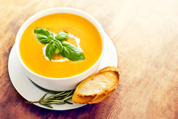 Squash soup with on wood table. Autumn Pumpkin soup served in a bowl, top view. Copy space.