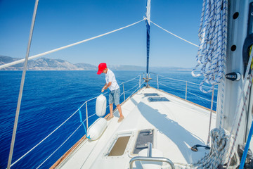 Little boy on board of sailing yacht on summer cruise. Travel adventure, yachting with child on family vacation.