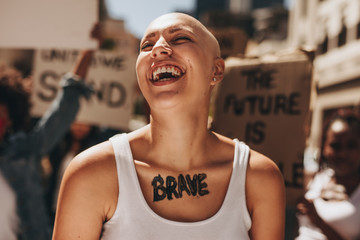 Brave woman with group of protesters in background - obrazy, fototapety, plakaty