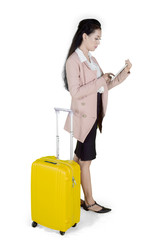 Young Asian businesswoman with suitcase using digital tablet