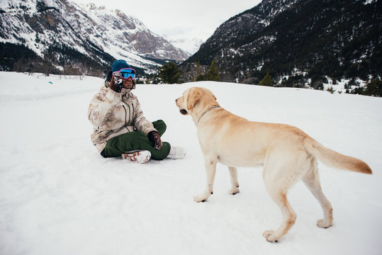 Friends playing with dog on the mountains, on th snowy ground