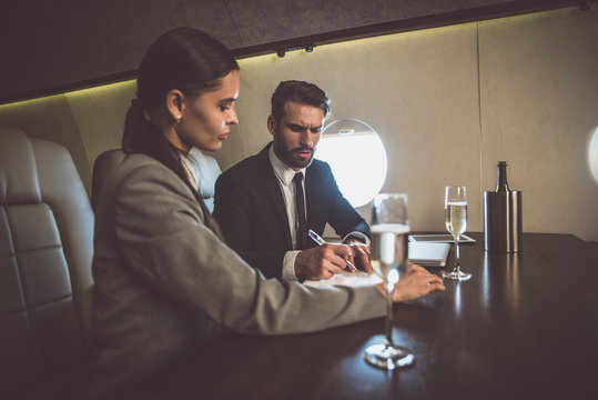 Business team flying on the private jet. Man and woman working during their flight to the meeting. Concept about transportations and salespeople