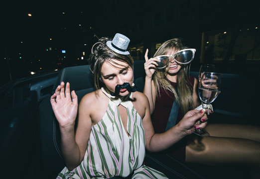 Party girls celebrate in Hollywood drinking champagne on a covertible car