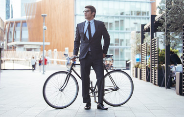 Handsome young business man with his modern bicycle.