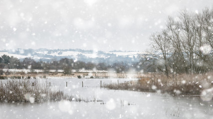 Winter landscape with snow falling and covering everything in English countryside