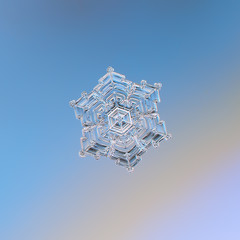 Snowflake glittering on smooth gradient background. Macro photo of real snow crystal: star plate with glossy surface, hexagonal symmetry, six short, broad arms and complex inner pattern.