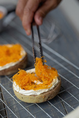 Cook preparing a sweet cake topping whipped cream and putting golden threads Thai Traditional Dessert on it