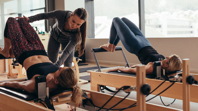 Female pilates trainer helping a pilates woman during training
