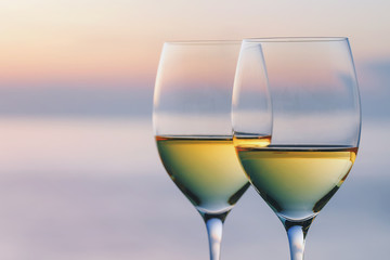 Two glasses of wine against the backdrop of the setting sun with space for text