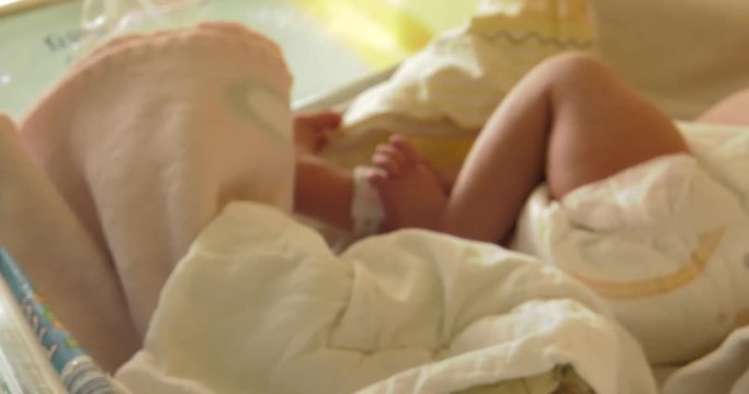 Little neonatal incubator, intensive hospital therapy: ICU, CCU, ICU, ITU. Tiny baby, small child, moving hands and fingers. Panning camera, Pan, Closeup