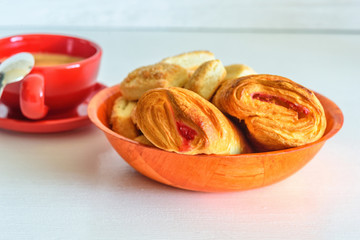 Puff pastry with jam and coffee mug on a white wooden background