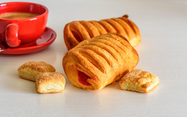 Puff pastry with jam and coffee mug on a white wooden background