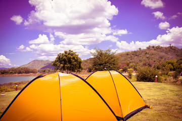 Big yellow family sized camping tent in the nice field with mountains on background