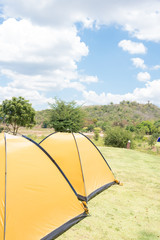 Big yellow family sized camping tent in the nice field with mountains on background