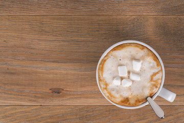 top view of fresh cappuccino with marshmallow on wood oak table