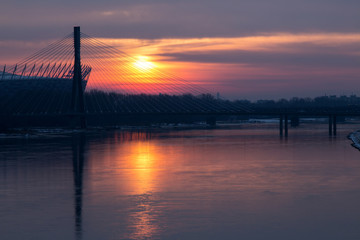 Fototapeta na wymiar Warsaw - sunrise on the Vistula with a railway bridge and football stadium