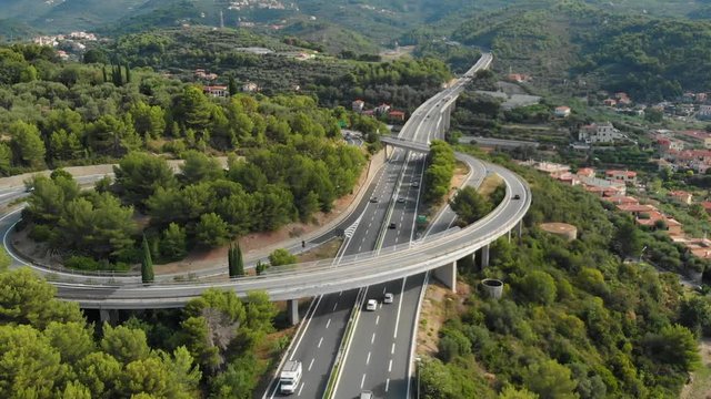 Aerial slow motion: flying near multiple lane highway crossing villages and forest hills (Autostrada dei Fiori - A10) Liguria Italy.