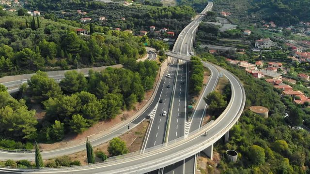Aerial slow motion: flying near multiple lane highway crossing villages and forest hills (Autostrada dei Fiori - A10) Liguria Italy.