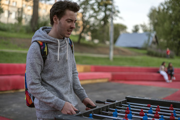dissatisfied young man playing tablefootball in park in moscow