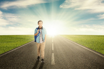 Preteen schoolboy walking on the road