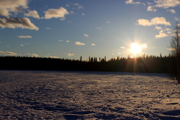 midnight sun over frozen lake in lapland, finland